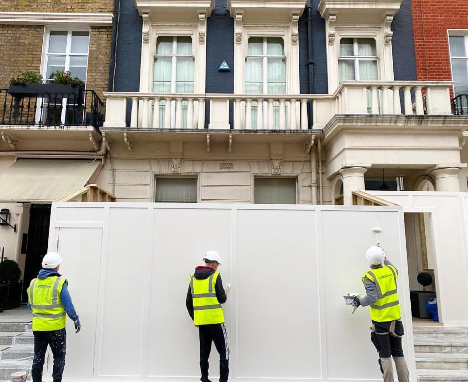 The team putting up the site hoarding in front of a stucco terrace